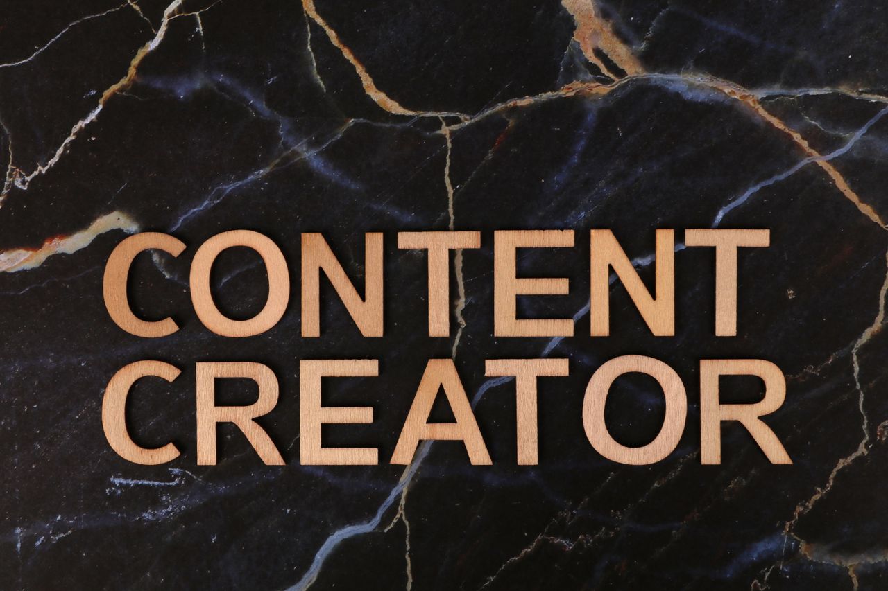 Wooden letters spelling CONTENT CREATOR on a dark marble background.