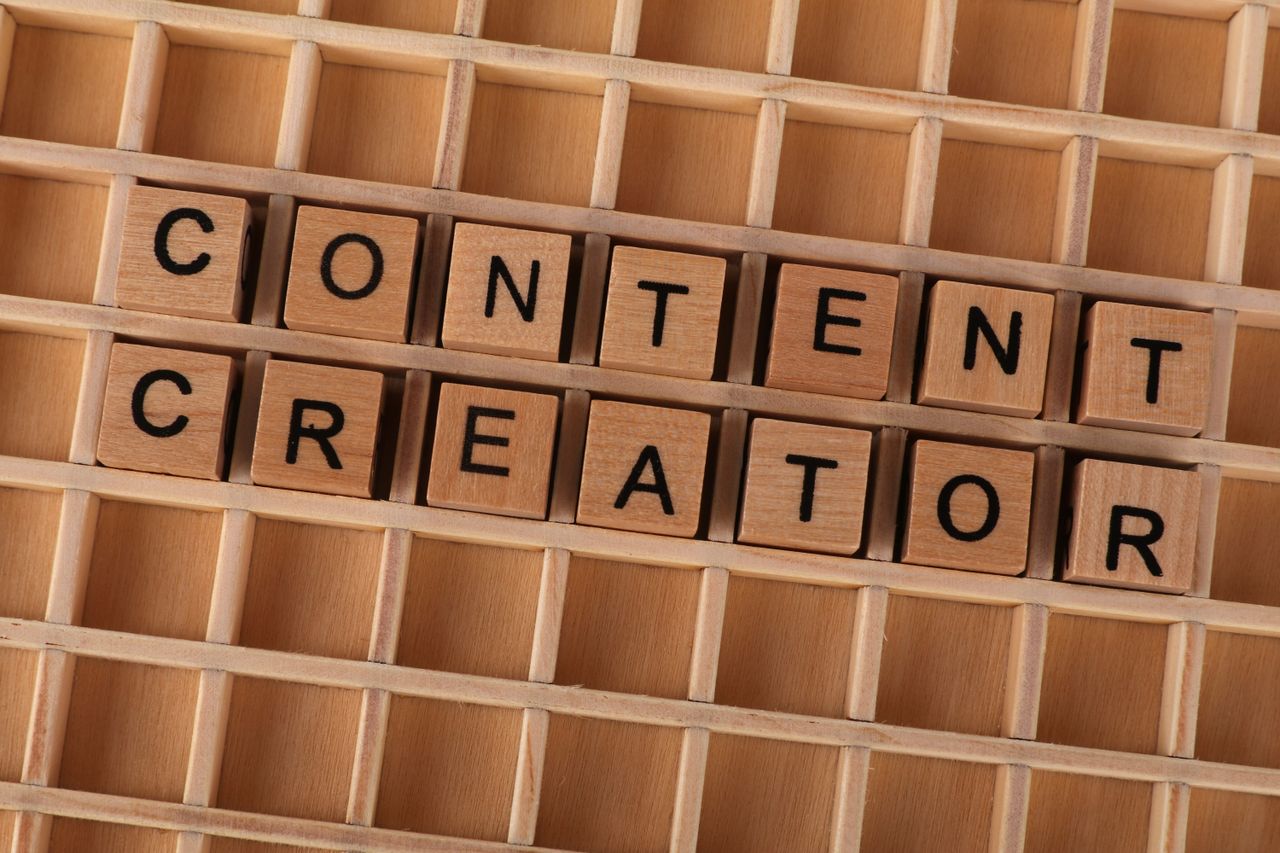 Wooden block letters spelling Content Creator on a grid background. Ideal for digital marketing themes.
